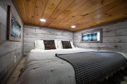 a bedroom with a large bed in a wooden room at Stunning Modern Tiny Home with Grill in Fredericksburg