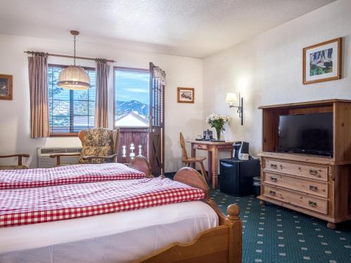 a bedroom with a bed and a television and a desk at Hotel Pension Anna in Leavenworth