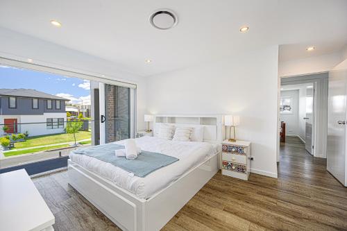 um quarto branco com uma cama grande e uma janela grande em Spacious 5 Bedroom 2.5 bathroom House in Gregory Hills em Narellan
