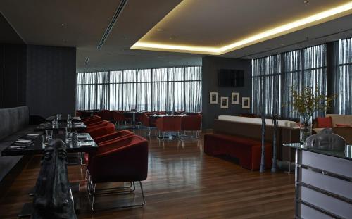 a restaurant with red chairs and tables and windows at Wyndham Grand Bangsar Kuala Lumpur in Kuala Lumpur