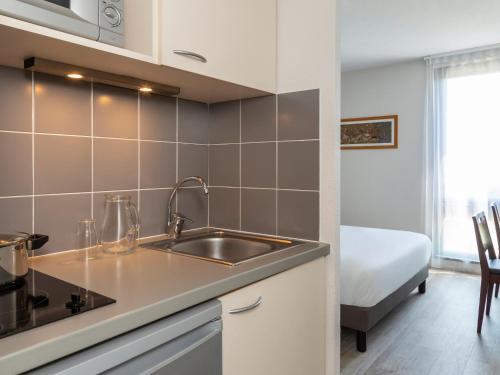 - une cuisine avec évier et un lit dans une chambre dans l'établissement Appart'Hotel - Gare TGV - Courtine - Confluence - 218, à Avignon