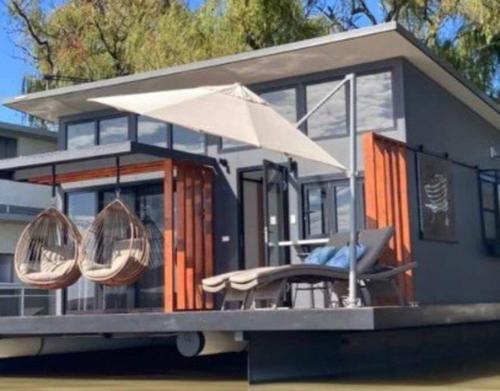 ein winziges Haus mit einer Veranda und einem Regenschirm in der Unterkunft Ark-imedes - Unique float home on the Murray River in White Sands