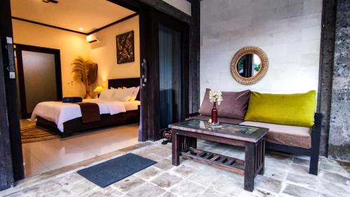 a bedroom with a couch and a bed and a table at Pondok Baruna Frangipani in Nusa Lembongan