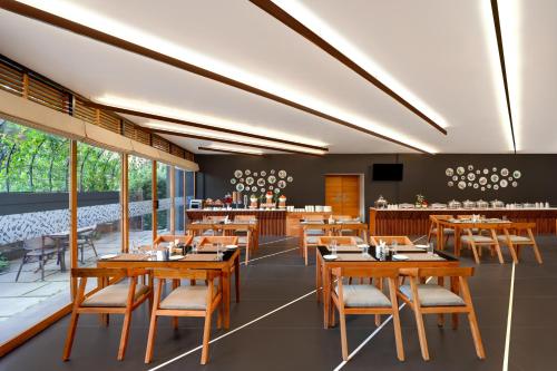 a dining room with wooden tables and chairs at Keys Prima By Lemon Tree Hotels, Thekkady in Thekkady