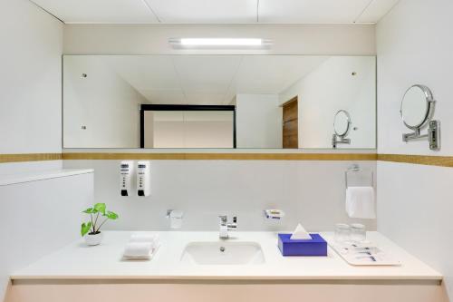 a bathroom with a sink and a mirror at Keys Prima By Lemon Tree Hotels, Thekkady in Thekkady