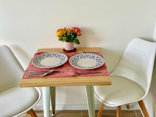 a table with two plates and a vase of flowers at Nuevo y Cómodo depto tipo Estudio in Valdivia