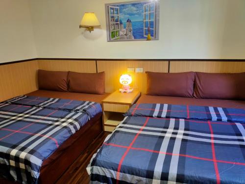 ein Schlafzimmer mit 2 Betten und einer Lampe auf einem Tisch in der Unterkunft Long Quan Ju in Wenquan