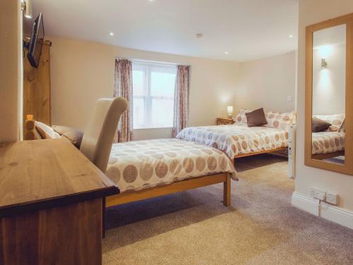 a bedroom with two beds and a mirror at The Queens Inn in St. Martin Guernsey