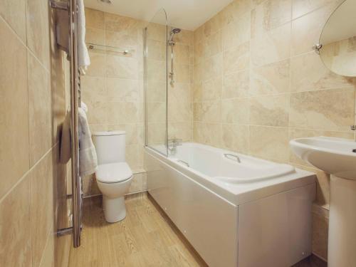 a bathroom with a toilet and a sink and a bath tub at The Queens Inn in St Martin Guernsey