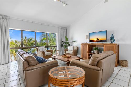 a living room with two couches and a tv at Culgoa Point Beach Resort in Noosa Heads