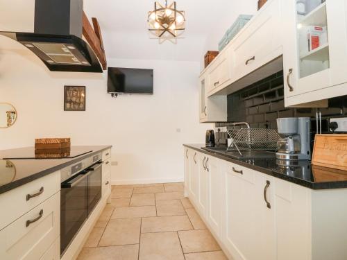 a kitchen with white cabinets and black counter tops at Y Beudy The Dairy in Oswestry