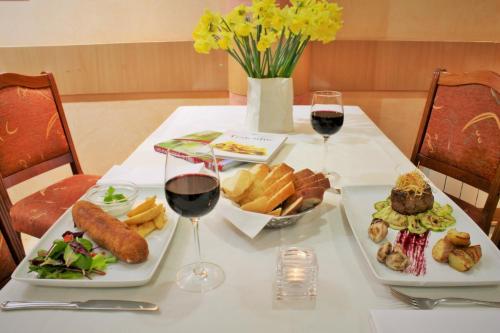 a table with two plates of food and two glasses of wine at Hotel Rex in Belgrade