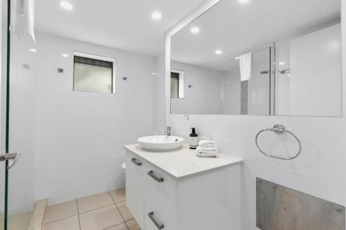 a white bathroom with a sink and a shower at Culgoa Point Beach Resort in Noosa Heads