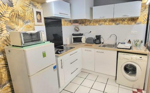 a small kitchen with a microwave and a washer and dryer at Studio et jardin "Le Coquet" in Jonzac