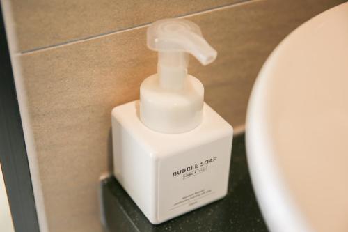 a white soap dispenser sitting next to a toilet at Rose Bay Hotel in Busan