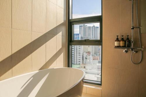 a bath tub in a bathroom with a window at Rose Bay Hotel in Busan