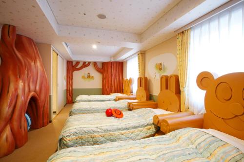 a group of four beds in a room with a teddy bear at Chitose Station Hotel in Chitose