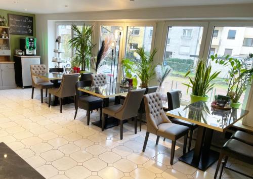 una sala da pranzo con tavoli, sedie e piante di Europa Hotel City a Saarbrücken