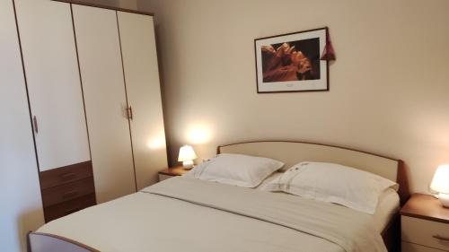 una camera con un letto bianco con due cuscini di Apartments Tomišić a Capodistria