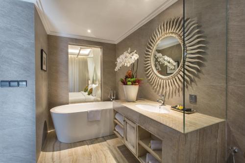 a bathroom with a tub and a sink and a mirror at Sense Canggu Beach Hotel in Canggu