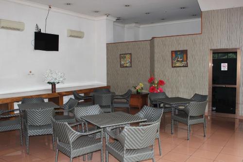 Hotel 678 Cawang powered by Cocotel في جاكرتا: مطعم بطاولات وكراسي وتلفزيون بشاشة مسطحة
