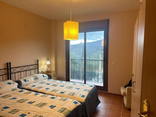 a bedroom with two beds and a large window at El Mirador de Las Hurdes in Ladrillar