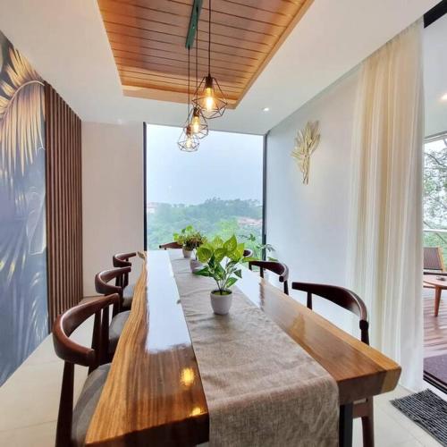 a dining room table with chairs and a large window at Villa Daun at Dago Village in Bandung