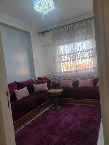 un soggiorno con divano viola e finestra di Lemssella meknes a Meknès