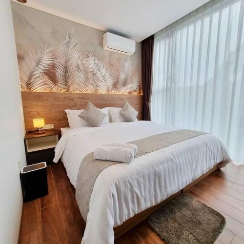 a bedroom with a large bed and a large window at Villa Daun at Dago Village in Bandung