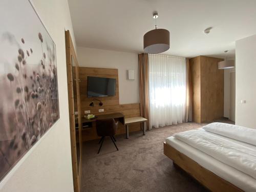 Schlafzimmer mit einem Bett, einem Schreibtisch und einem TV in der Unterkunft Hotel-Pension Scharl am Maibaum in Eitting