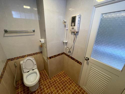 a bathroom with a toilet and a phone on the wall at Man u Apartment in Chaiyaphum