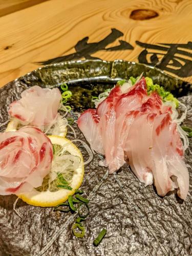a plate with meat and lemon slices on a table at private accommodation隠岐貸切古民家宿くすぶるハウス in Okinoshima
