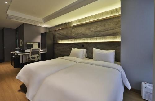 a large white bed in a room with a desk at Rose Bay Hotel in Busan
