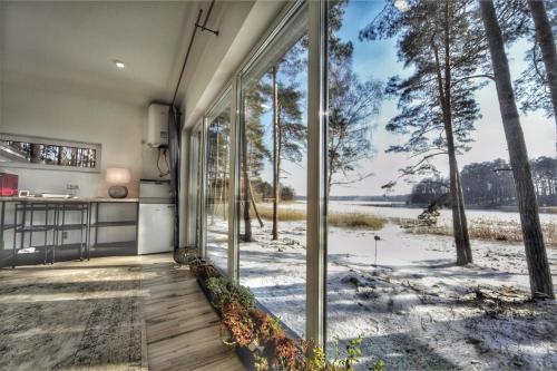 a kitchen with a large glass door with a view of a snowy field at GaujaClub - our BOSE and Bang&Olufsen lofts on a lake in Gauja