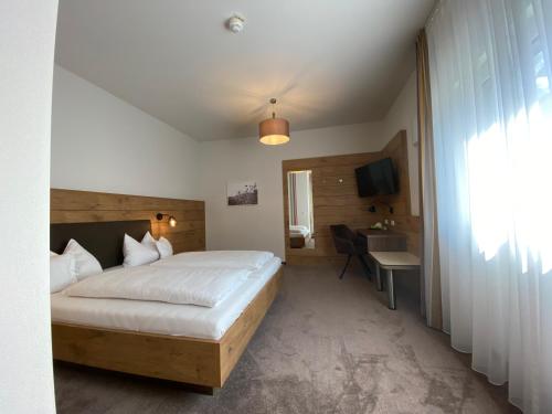 a bedroom with a bed and a desk and a television at Hotel-Pension Scharl am Maibaum in Eitting