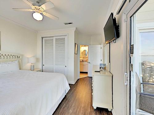a white bedroom with a bed and a flat screen tv at Baywatch #B1 in Pensacola Beach