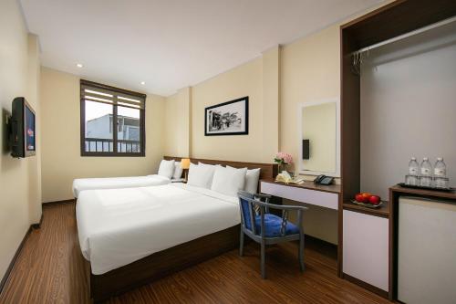 um quarto de hotel com uma cama grande e uma cadeira em Queen Cafe Hotel & Pub em Hanói