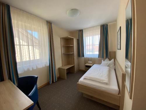 a hotel room with a bed and a desk and window at Hotel-Pension Scharl am Maibaum in Eitting