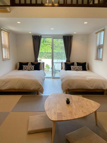 two beds in a room with a coffee table at Villa Sunbeams ヴィラ・サンビームス in Kin