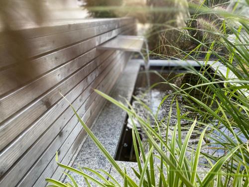 a wooden bench in a garden with plants at Hotel-Pension Scharl am Maibaum in Eitting