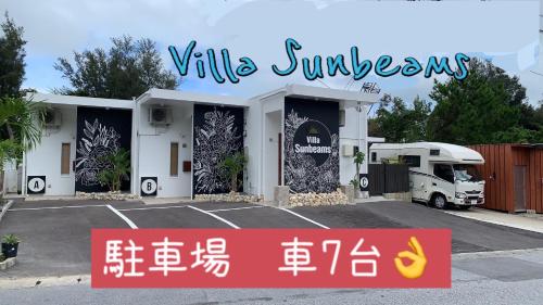 a building with a sign in a parking lot at Villa Sunbeams ヴィラ・サンビームス in Kin