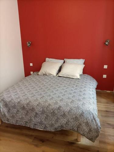 Ce lit se trouve dans une chambre dotée d'un mur rouge. dans l'établissement Appartement 1er étage, à Largentière