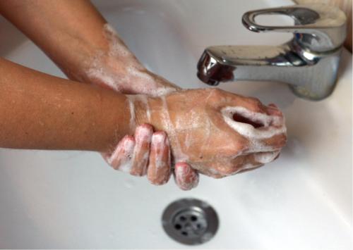 a person washing their hands in a sink at Zingle Stay Airport Hotel in Chennai