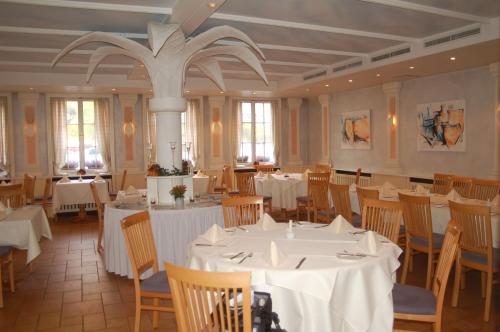 Schlosshotel Ingelfingen في Ingelfingen: غرفة طعام مع طاولات وكراسي بيضاء