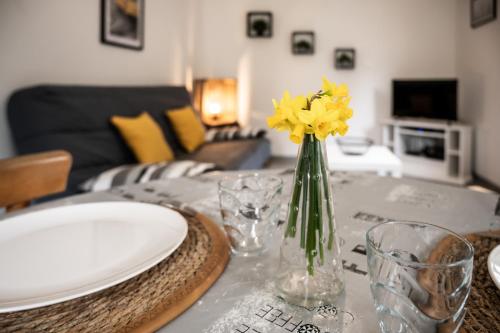 einen Tisch mit einer Vase mit gelben Blumen darauf in der Unterkunft Gite Pak'Home maison à la campagne 3 étoiles avec wifi in Lombray