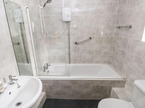 a bathroom with a shower and a tub and a sink at Sun Rise Cottage in Saundersfoot