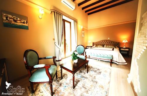 a bedroom with a bed and chairs and a window at SOFIA BOUTIQUE HOTEL in Kérynia