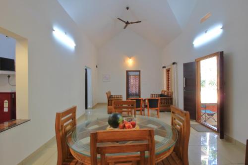 a dining room with a glass table and wooden chairs at TreeSong Villa - Tranquil Forest Villa in Wayanad in Sultan Bathery