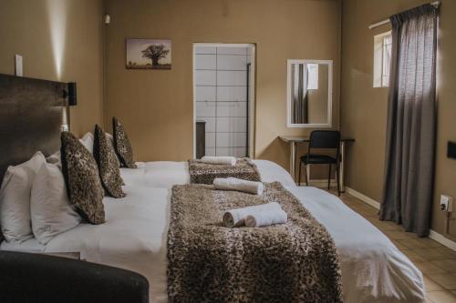 a bedroom with a large white bed with towels on it at Casa Leitao Lodge in Phalaborwa
