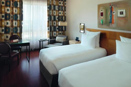 a hotel room with two beds and a chair at Mövenpick Ambassador Hotel Accra in Accra